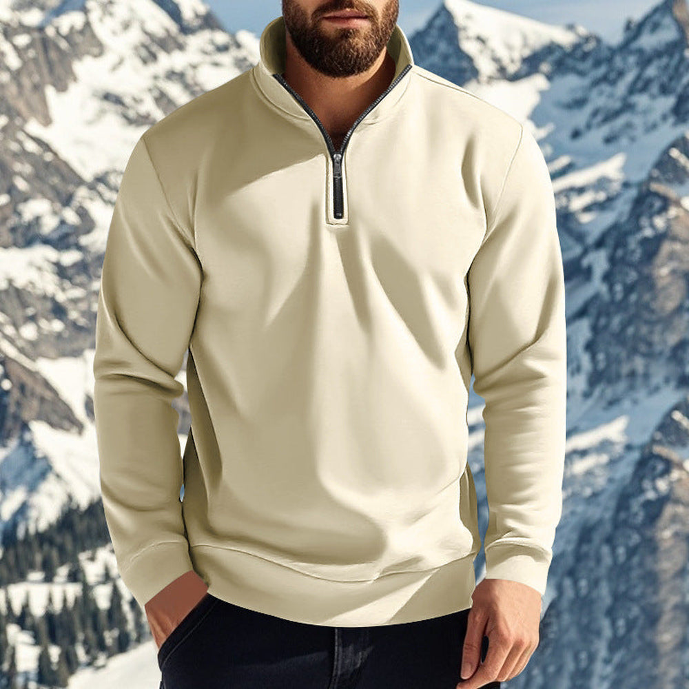 Man wearing a cream quarter zip jumper in front of snowy mountains, one hand in his pocket | Chaps London