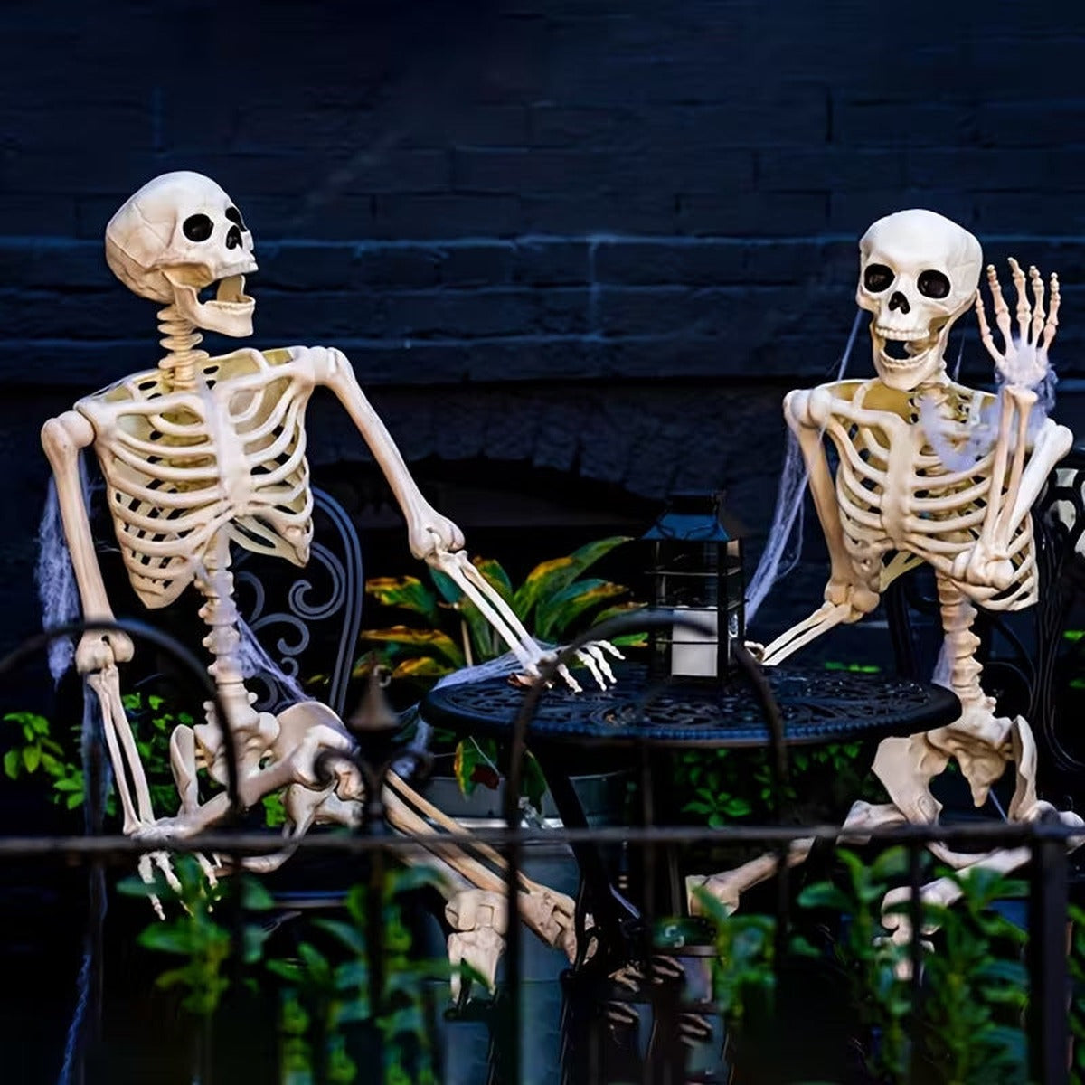 Two skeletons at a garden table as Halloween decoration