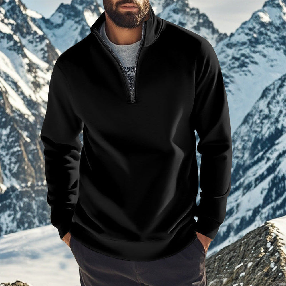 Man wearing a black quarter zip jumper over a grey T-shirt with mountains behind him | Chaps London