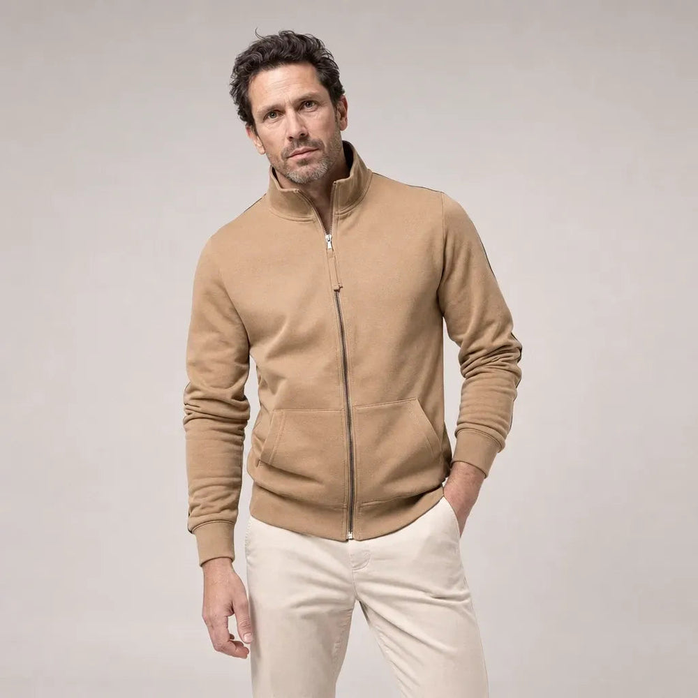 Man wearing a camel zip-up sweatshirt with cream chinos, one hand in his trouser pocket | Chaps London