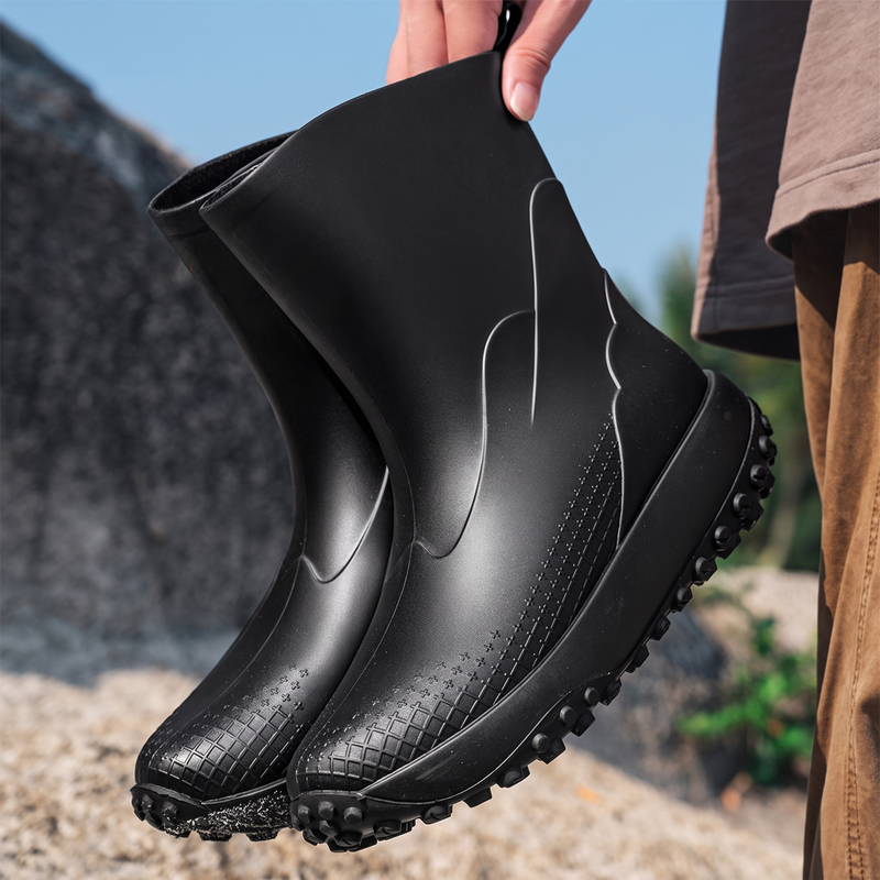 Black rubber boots with ridged sole, held by hand outdoors | Chaps London
