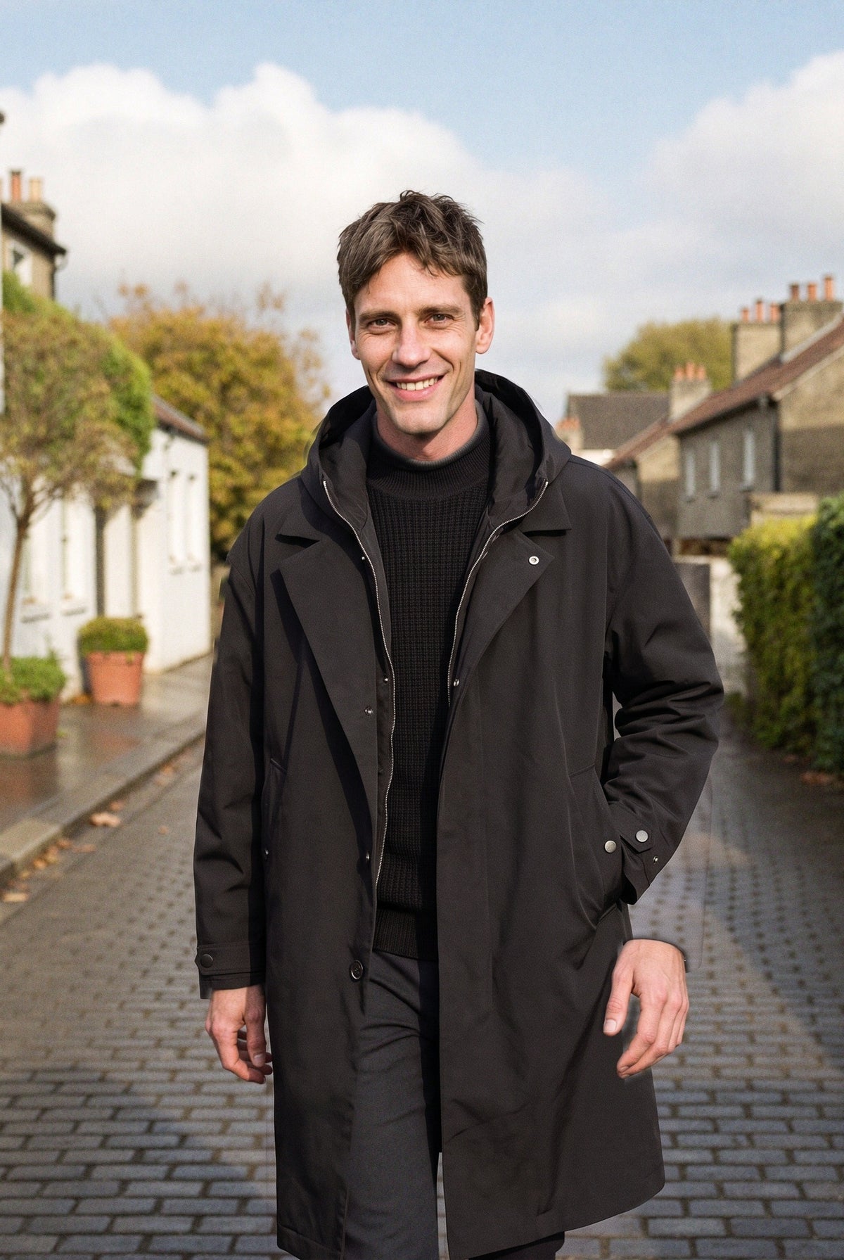 Men's long hooded raincoat in black, worn in a London mews