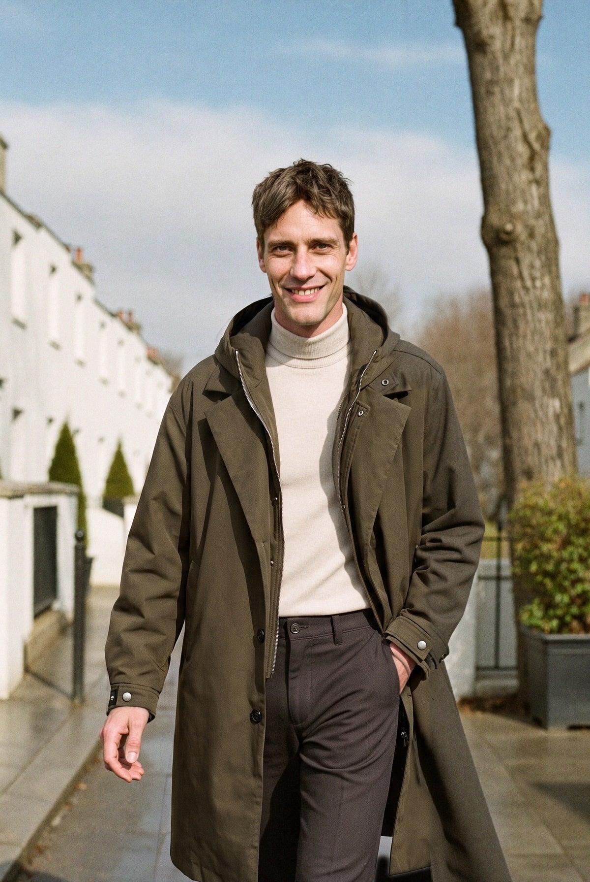 Men's long hooded raincoat in khaki, worn on a London street