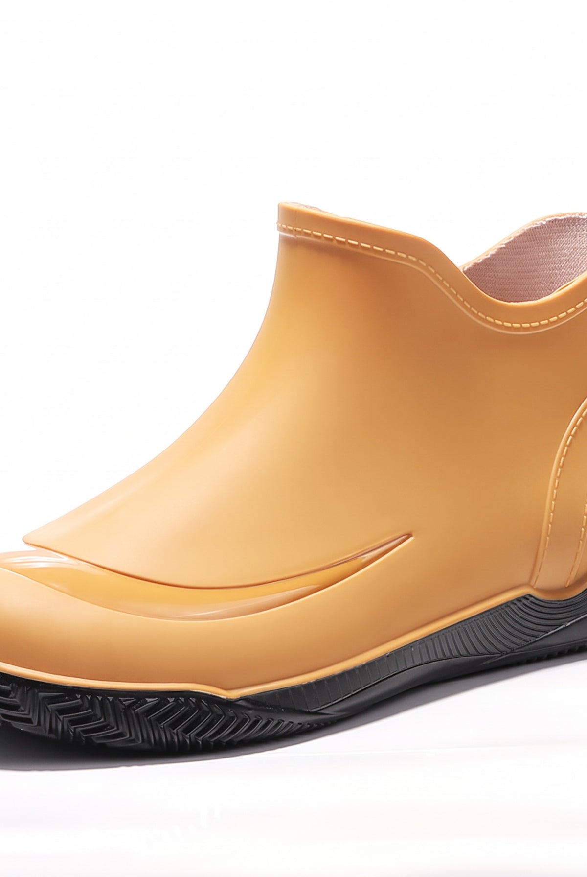 Yellow short welly with a black treaded sole, side view