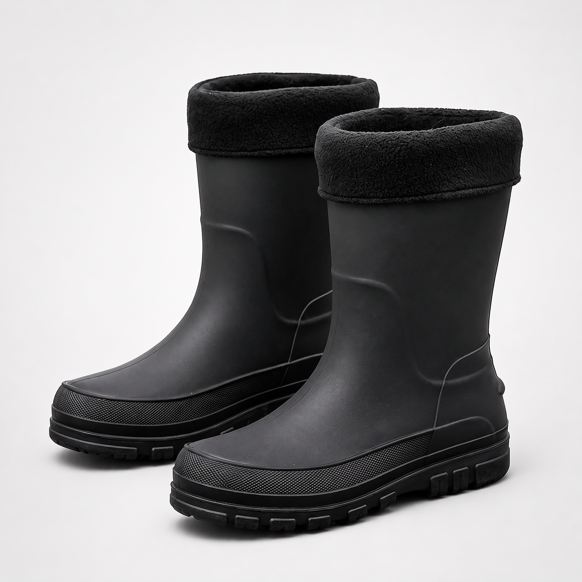 A pair of black insulated rubber rain boots with black fleece cuffs, shown at a three quarter angle on a plain light grey studio background.