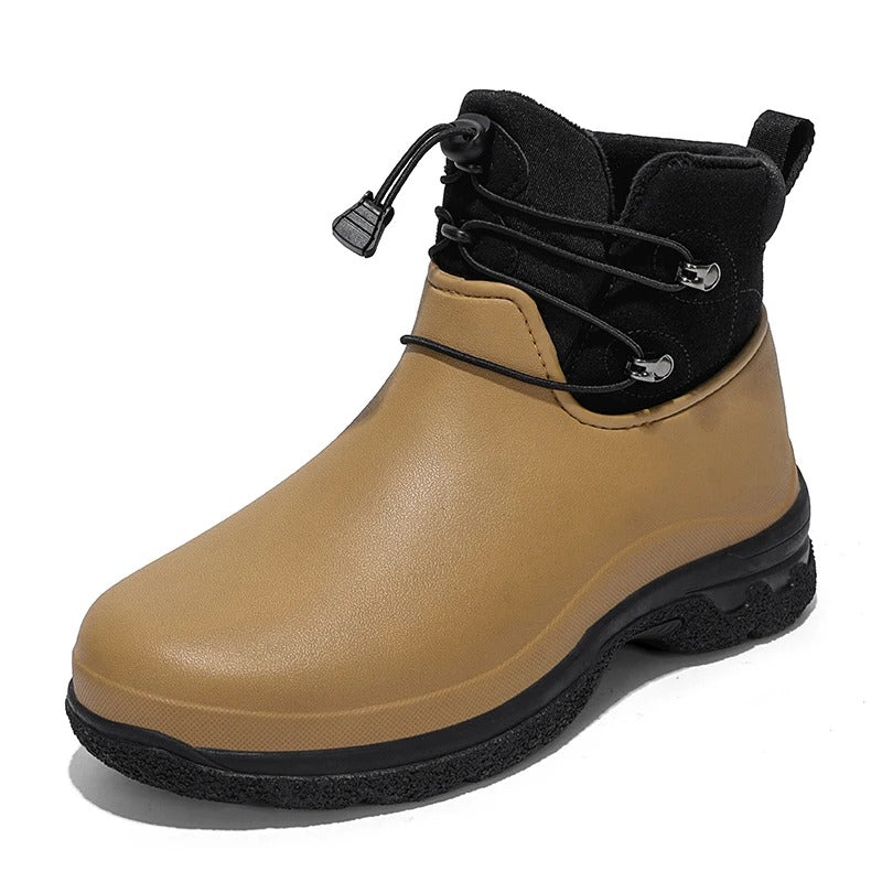 Three quarter studio view of a tan rubber ankle rain boot with a black fabric collar, elastic toggle lacing, a pull tab and a chunky black textured sole on a white background.