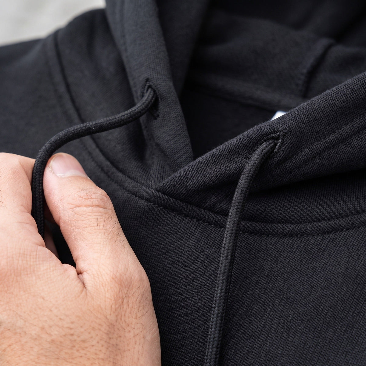 Close-up of black hoodie drawstring and hood, worn by a person | Chaps London