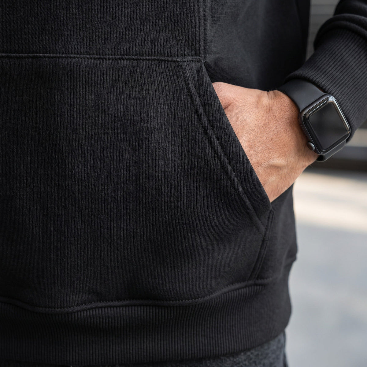 Black hoodie kangaroo pocket worn by person with smartwatch visible | Chaps London