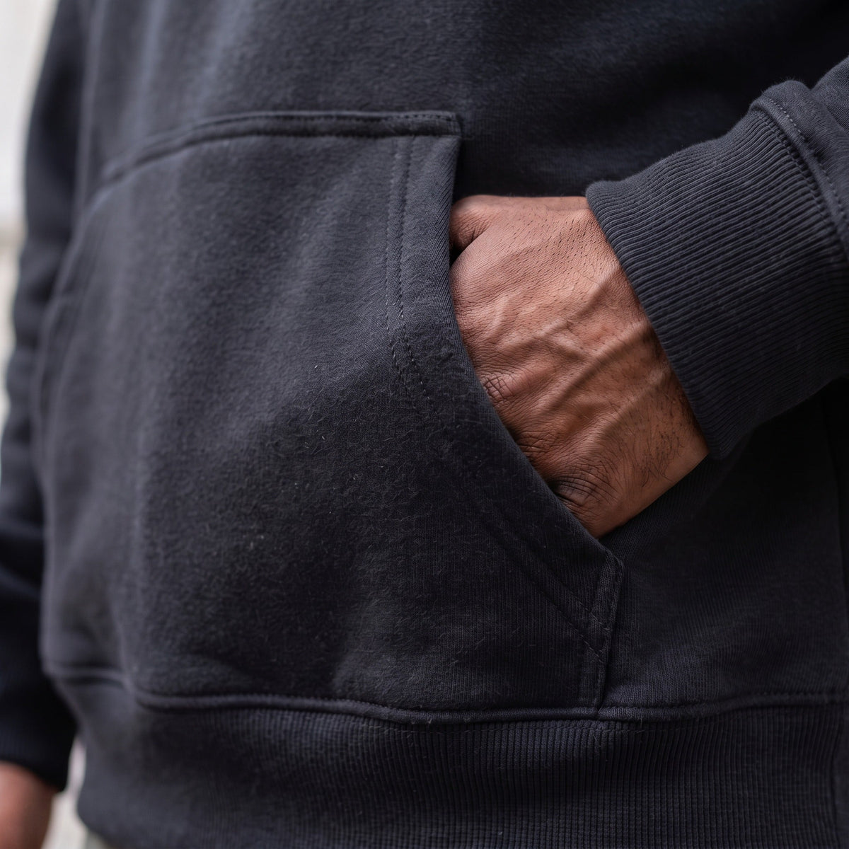 Black hoodie pocket close-up, worn by person with hand inside | Chaps London