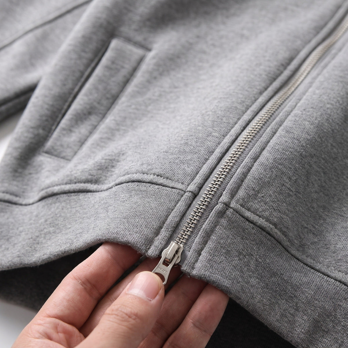 Close-up of hand unzipping grey two-way zipper on cropped hoodie | Chaps London