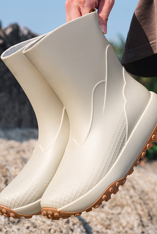 Beige men's wellies with non-slip sole, held in the hand