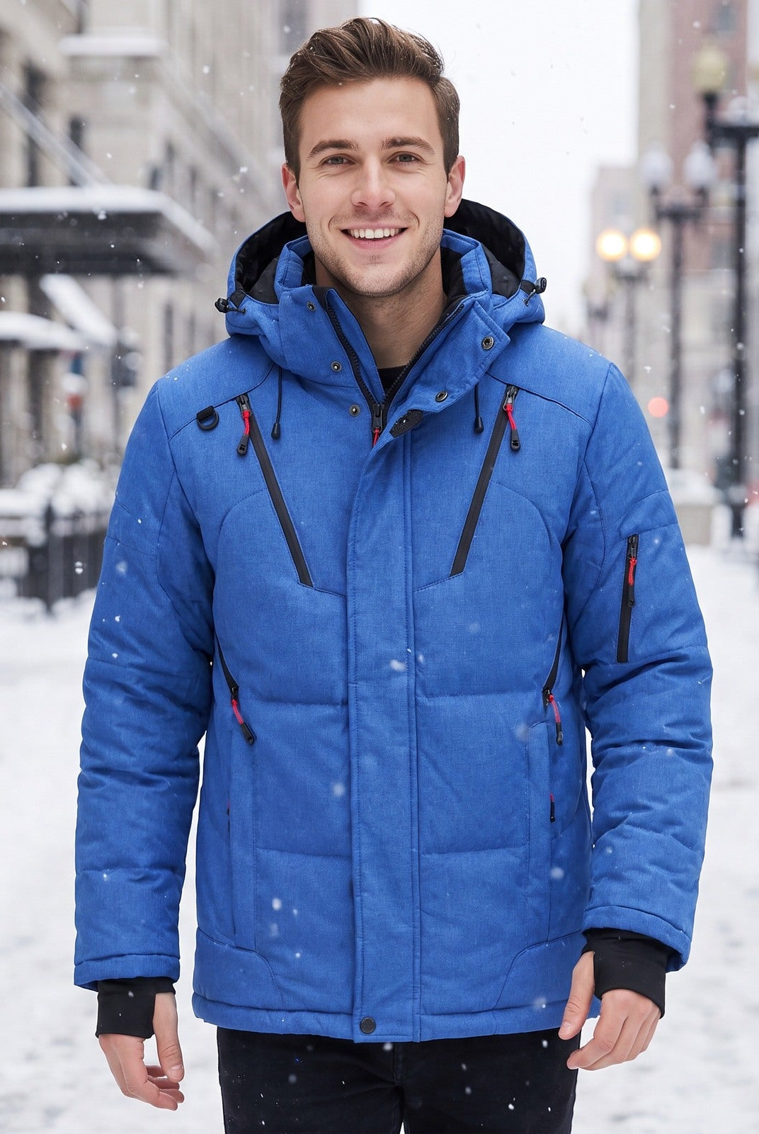 Man wearing blue padded winter jacket with hood, standing outdoors in snow | Chaps London