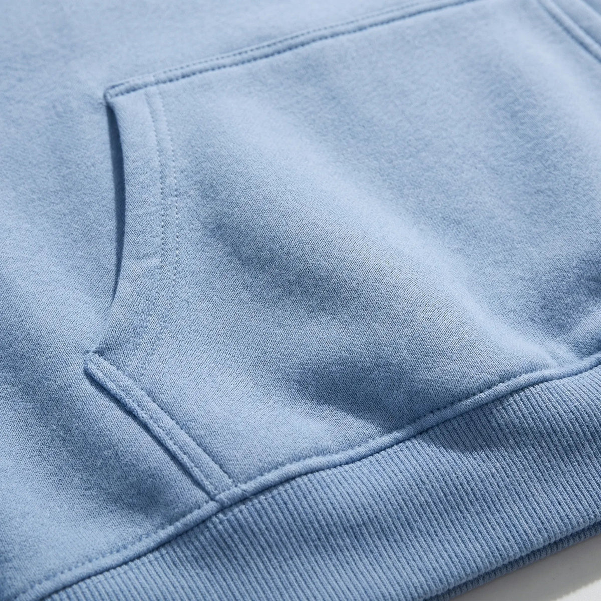Close-up of light blue hoodie fabric showing pocket and ribbed hem detail | Chaps London
