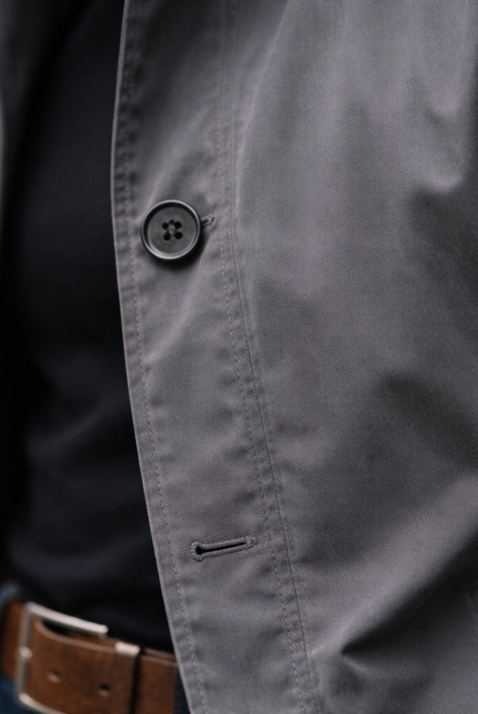 Gray cotton rain mac button detail worn by person, close-up view | Chaps London