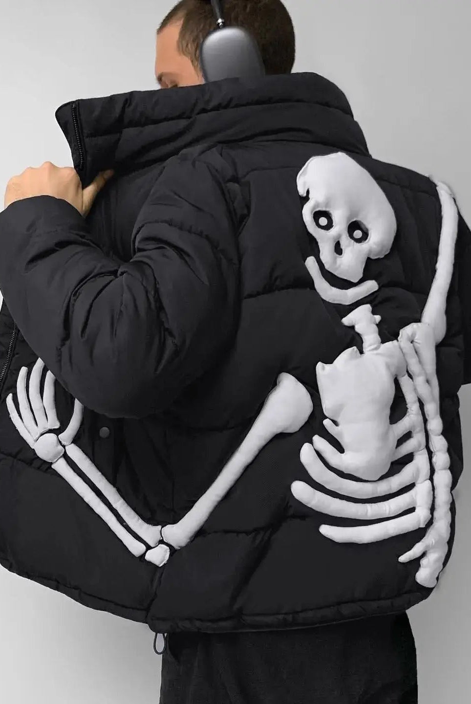 Black puffer jacket with raised white skeleton design worn by man | Chaps London