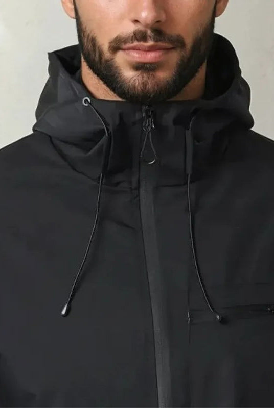 Black hooded rain jacket with zip pocket worn by man, close-up view | Chaps London