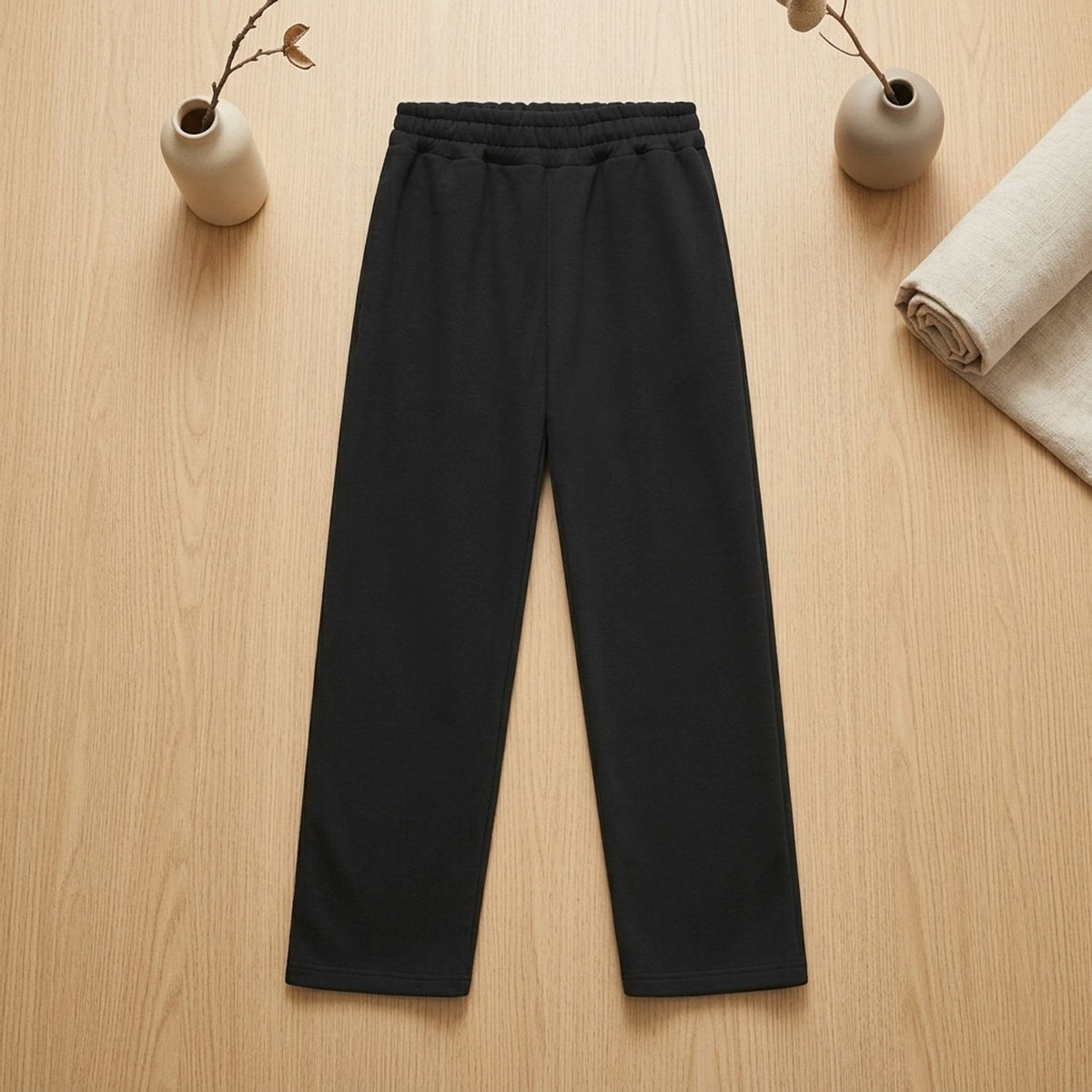 Black straight leg joggers with elastic waistband, laid flat on wooden surface | Chaps London