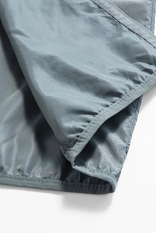 Grey nylon windbreaker fabric close-up showing zipper and stitched hem detail | Chaps London