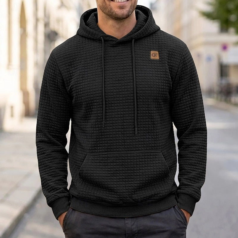 Black quilted-texture hoodie with chest patch worn by man outdoors | Chaps London