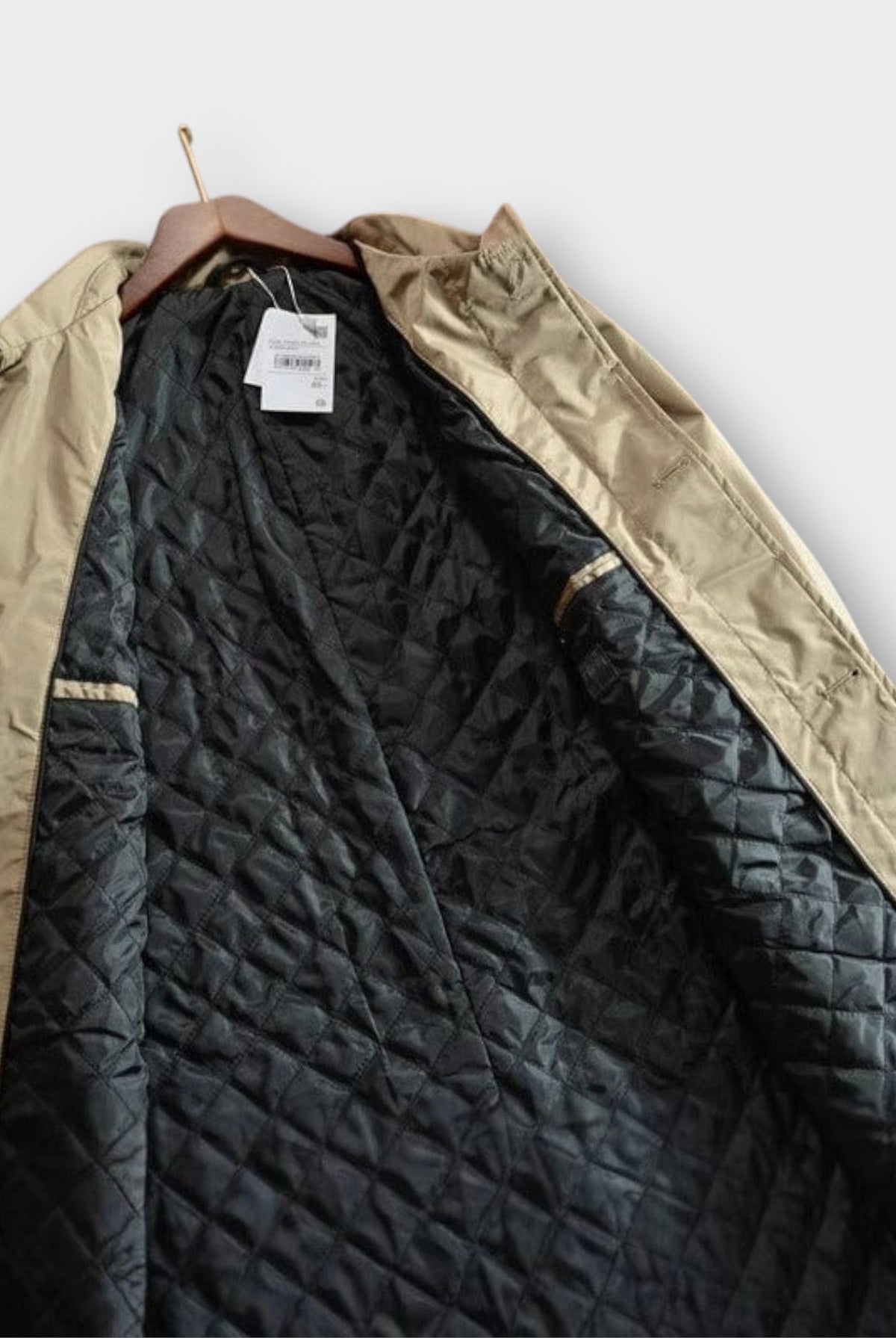 Beige rain mac on hanger showing black quilted lining detail | Chaps London