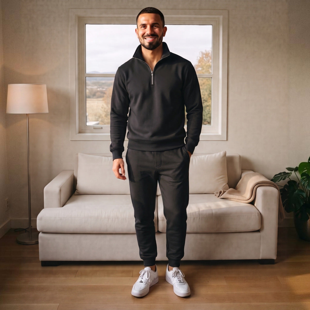 Man wearing black half-zip tracksuit with joggers, standing in living room | Chaps London