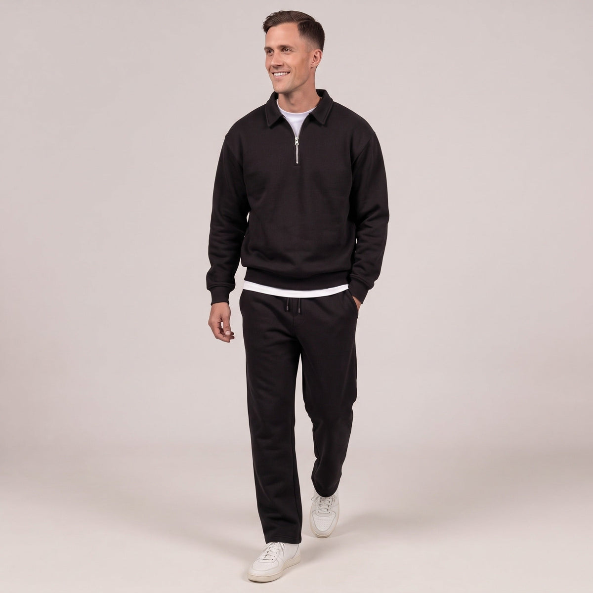 Man wearing black quarter zip sweatshirt with matching black joggers, standing | Chaps London