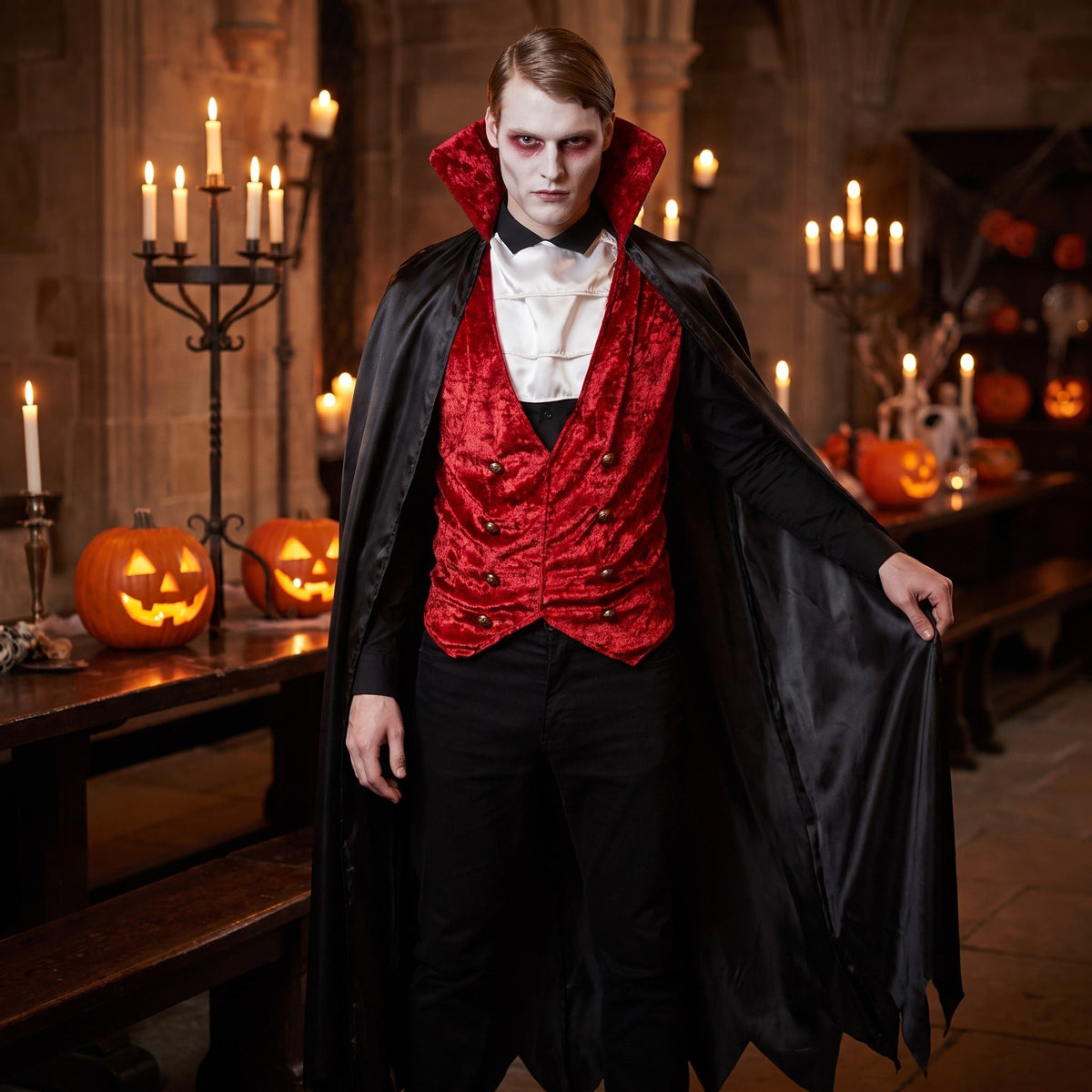 Man wearing black cape, red velvet waistcoat, white cravat costume indoors | Chaps London