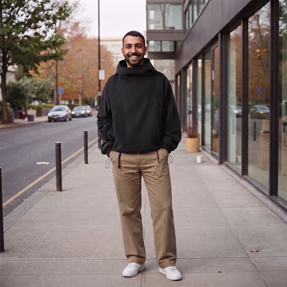 Man wearing black funnel neck hoodie with tan trousers outdoors | Chaps London