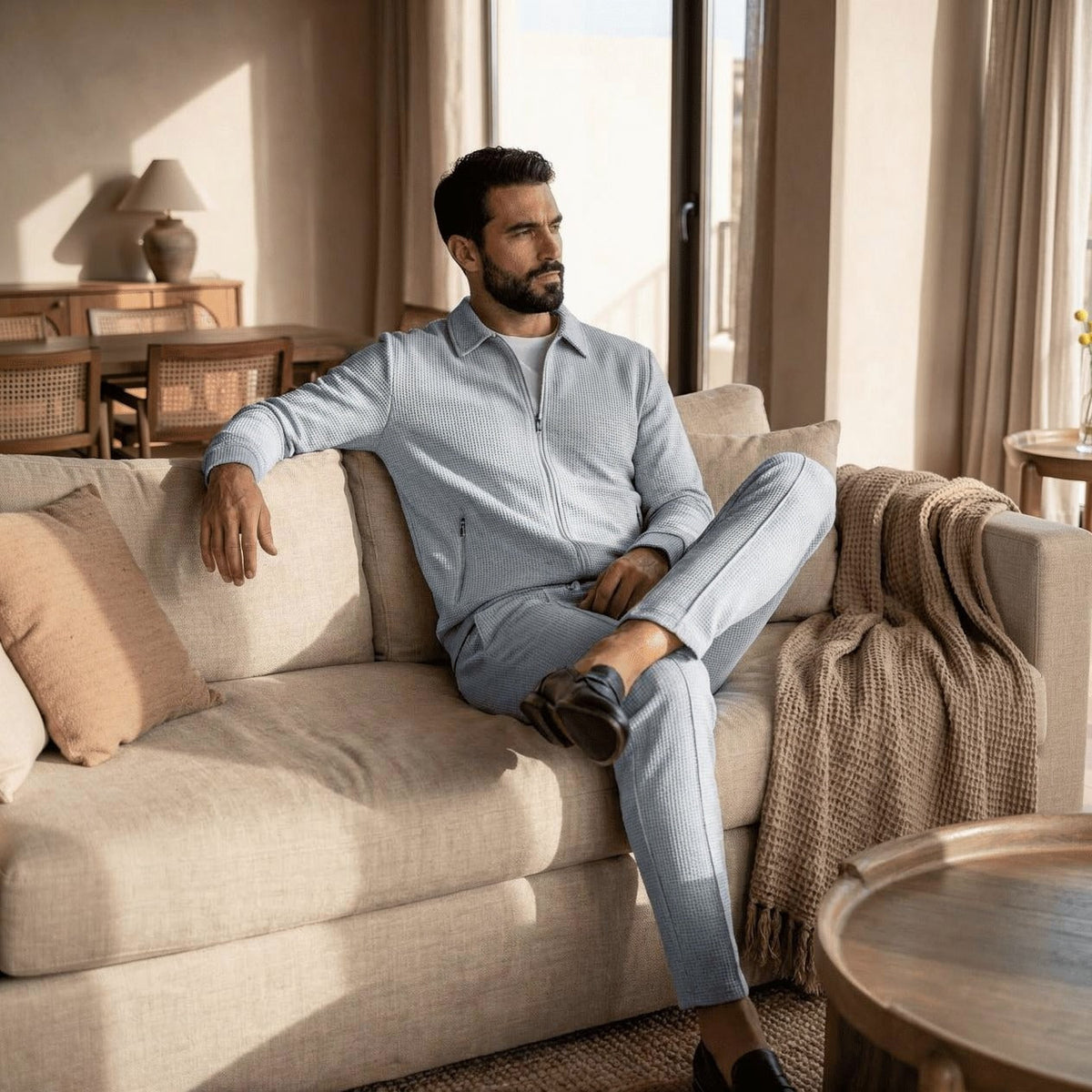 Man wearing light grey waffle-texture tracksuit with zip jacket, seated on sofa | Chaps London