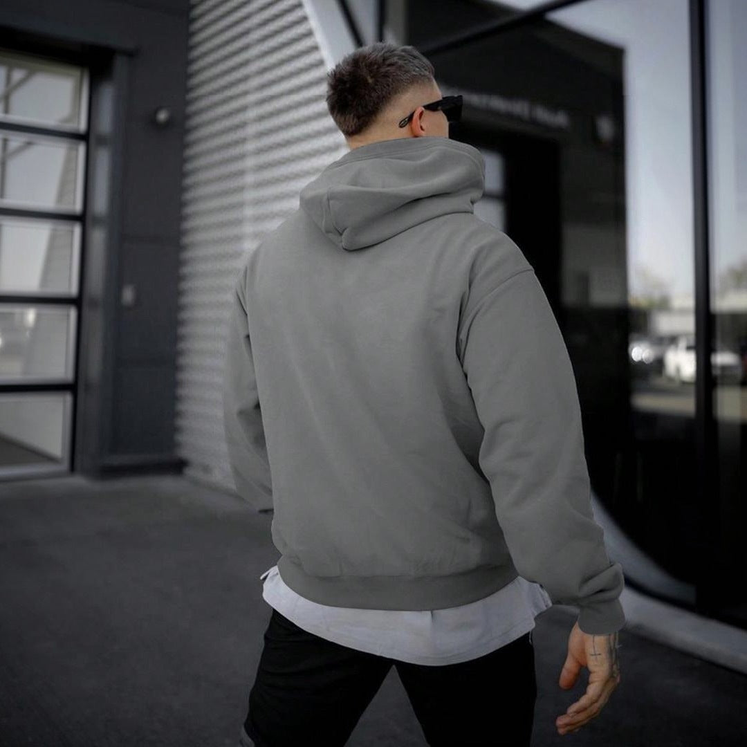 Man wearing plain grey hoodie with kangaroo pocket, viewed from behind outdoors | Chaps London