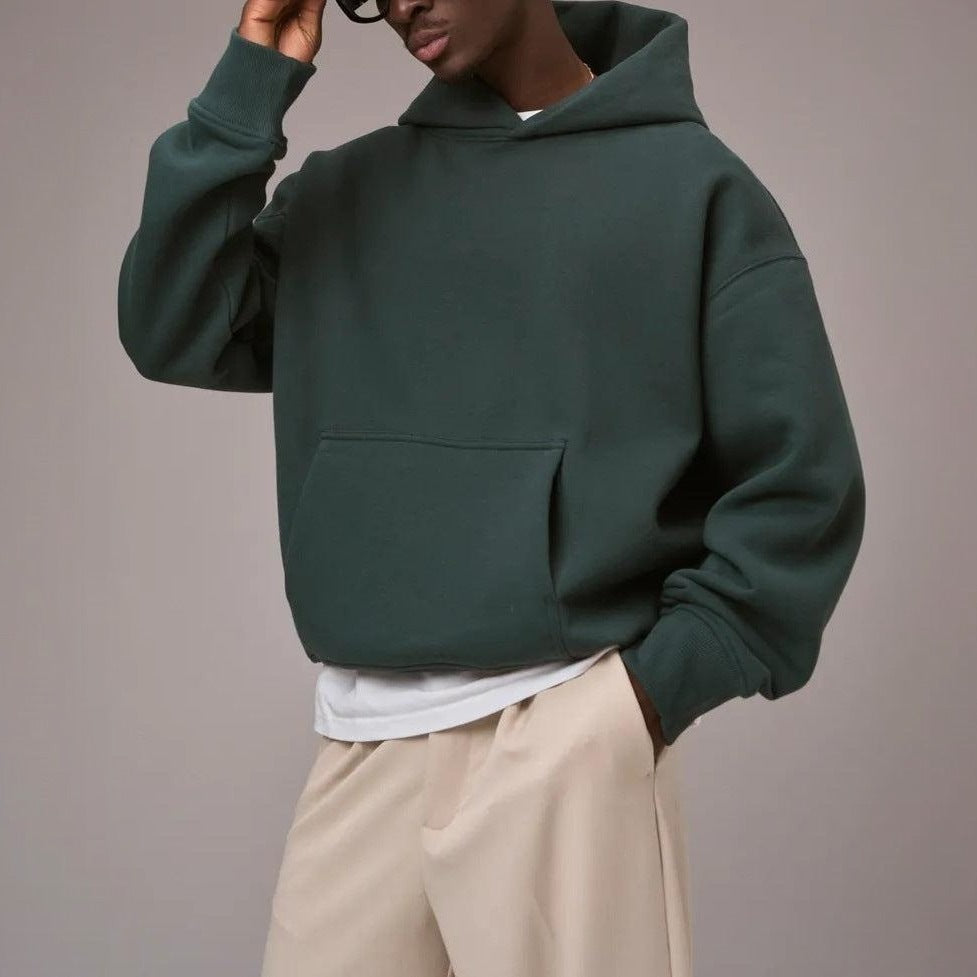 Man wearing dark green oversized hoodie with beige trousers, worn outdoors | Chaps London