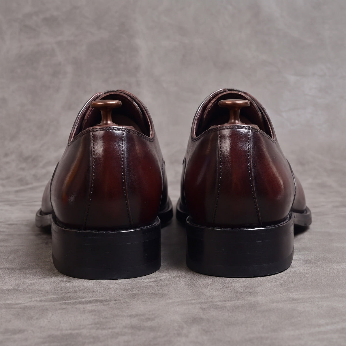 Burgundy oxford dress shoes rear view, flat lay on gray surface | Chaps London