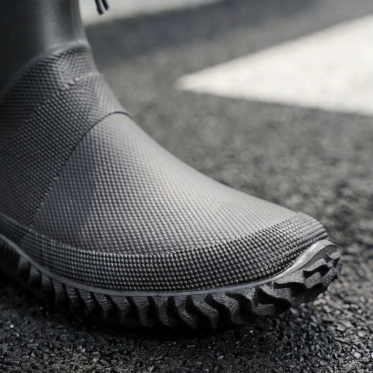 Black textured ankle boot with ridged sole, worn on foot outdoors | Chaps London