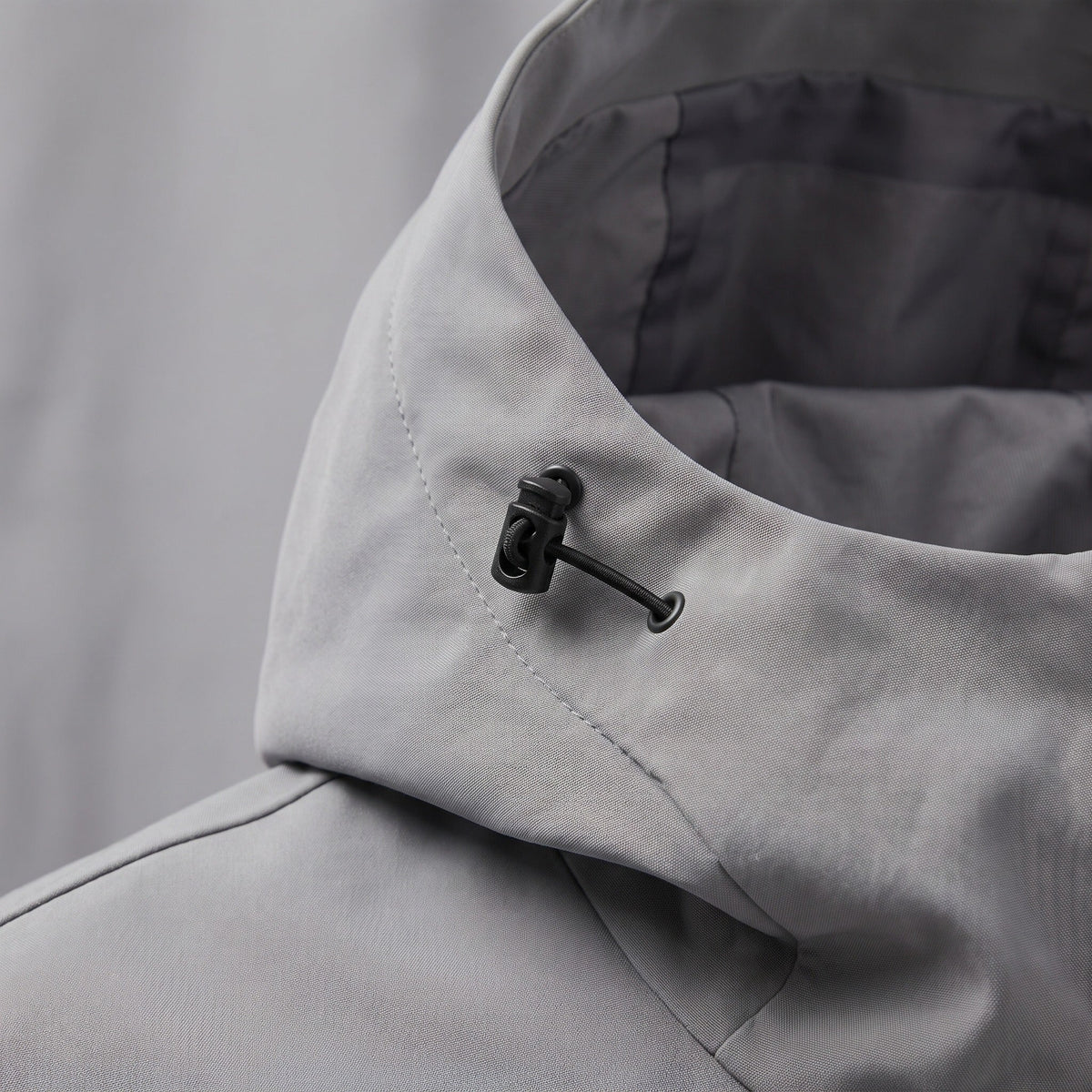 Gray rain jacket close-up showing hood collar and toggle drawstring detail | Chaps London