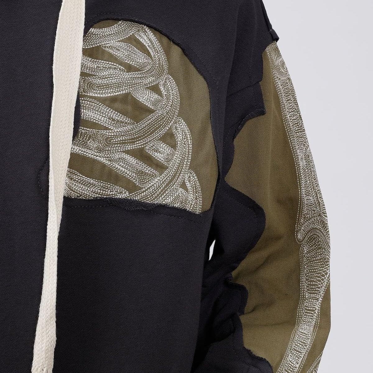 Close-up of black hoodie with olive panels and bone embroidery detail | Chaps London