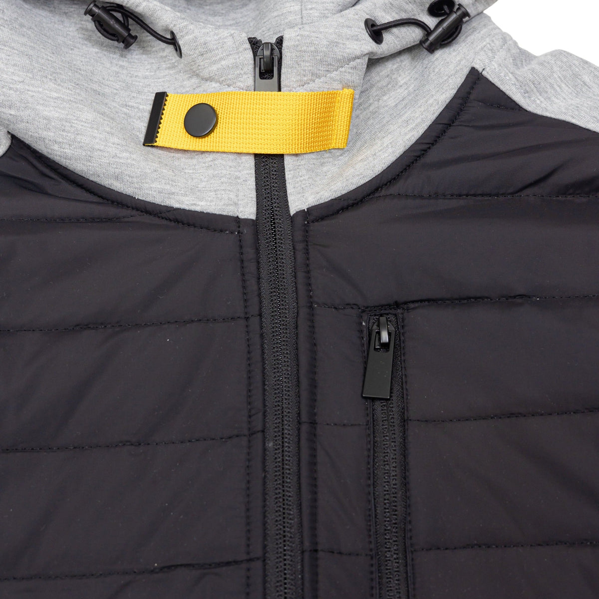 Close-up of black quilted jacket with grey hood and yellow zipper pull | Chaps London