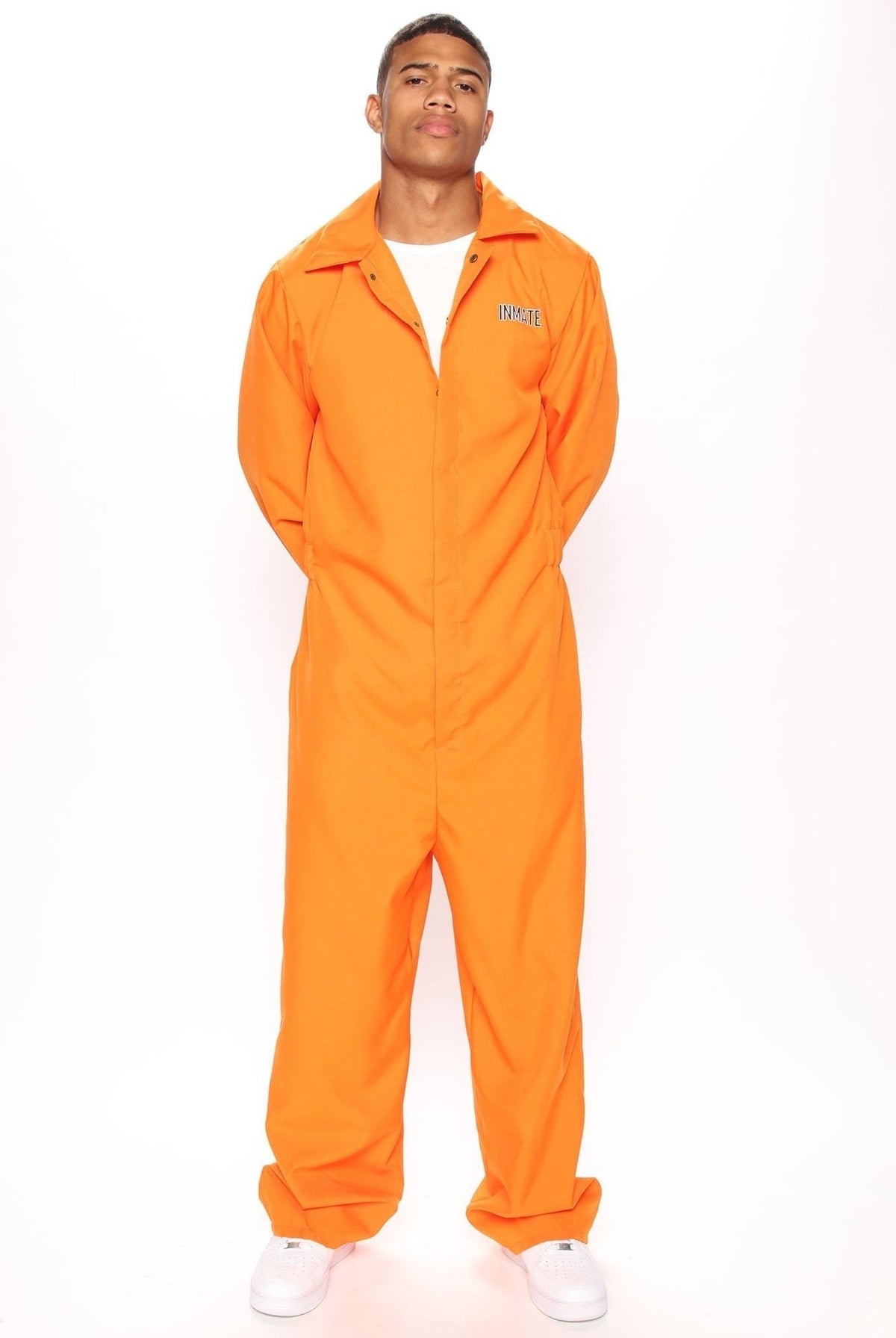 Man wearing orange jumpsuit costume with white sneakers, standing against plain background | Chaps London