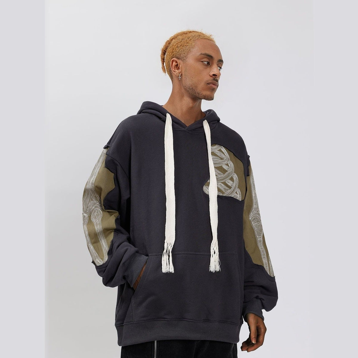 Dark gray hoodie with camo patchwork sleeve, worn by man, drawstrings visible | Chaps London