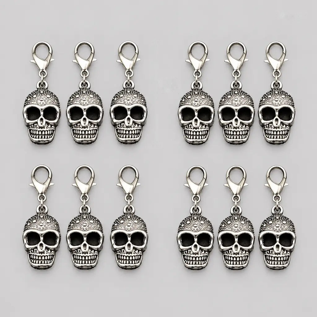 Twelve silver skull charms with lobster clasps, laid flat in rows | Chaps London