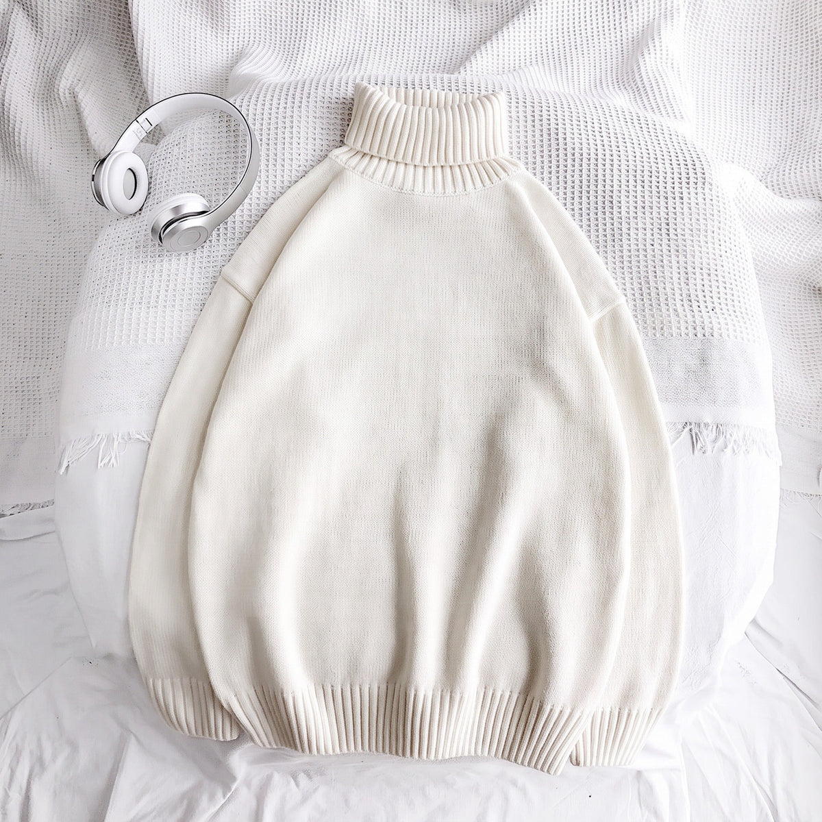 Cream knit turtleneck sweater laid flat on white bedding, folded | Chaps London