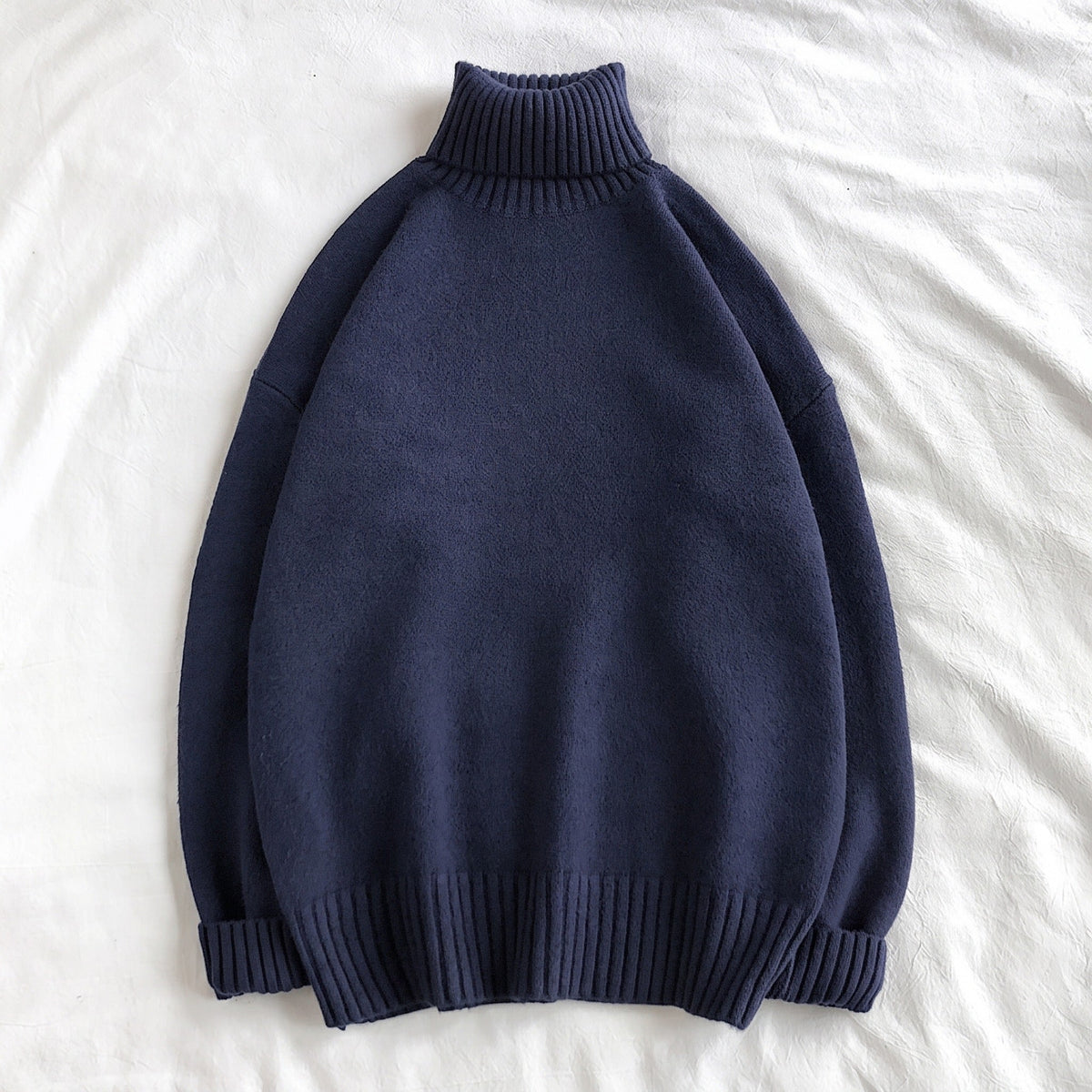Navy blue oversized turtleneck sweater with ribbed knit, laid flat on fabric | Chaps London