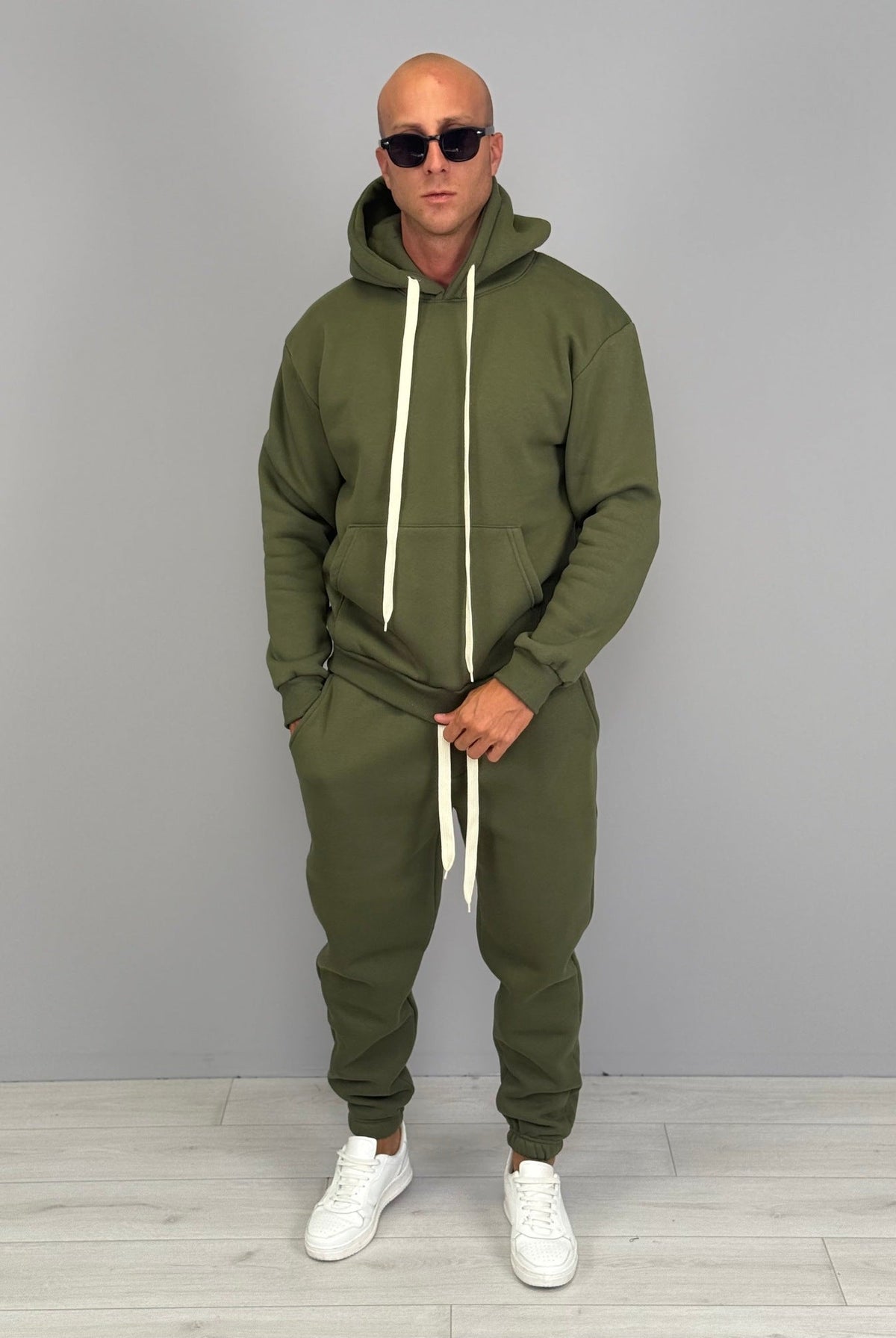 Man wearing olive green hoodie tracksuit with matching cuffed joggers, sunglasses | Chaps London