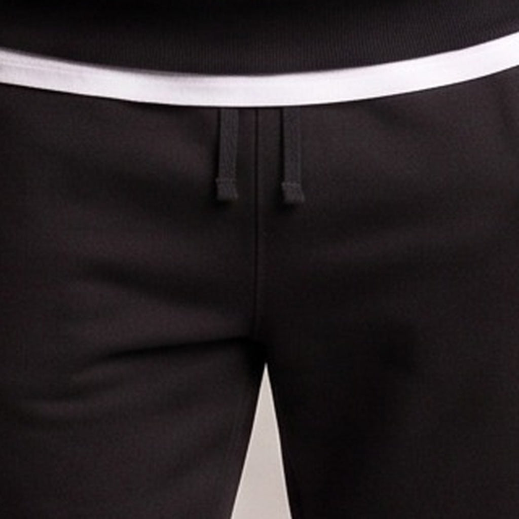 Close-up of black joggers with white waistband and drawstring detail, worn by person | Chaps London