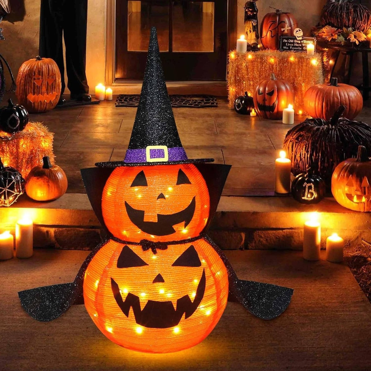 Light-up Halloween pumpkin with witch hat and cape on the porch