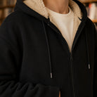 Men's zip-through hoodie in black, close-up of the sherpa-lined hood and the zip