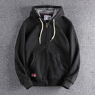 Black zip-up hoodie with a grey-lined hood and off-white drawcords, laid flat | Chaps London
