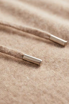 Men's knitted hooded jumper in beige, close-up of the metal tips of the drawstring