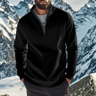 Man wearing a black quarter zip jumper over a grey T-shirt with mountains behind him | Chaps London