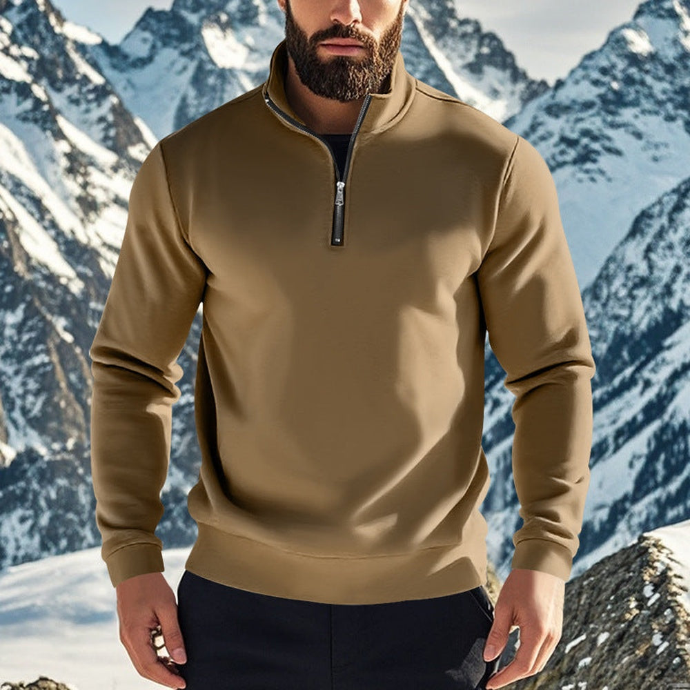Man wearing a brown quarter zip jumper with dark trousers against a snowy mountain backdrop | Chaps London