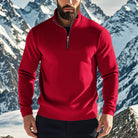 Man wearing a red quarter zip jumper open at the neck over a black T-shirt, snowy peaks behind him | Chaps London